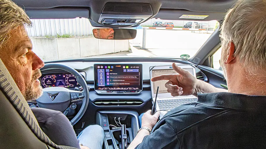 Zwei Personen sitzend im Auto fotografiert.