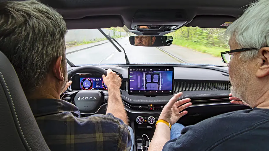 Zwei Personen sitzend im Auto fotografiert.