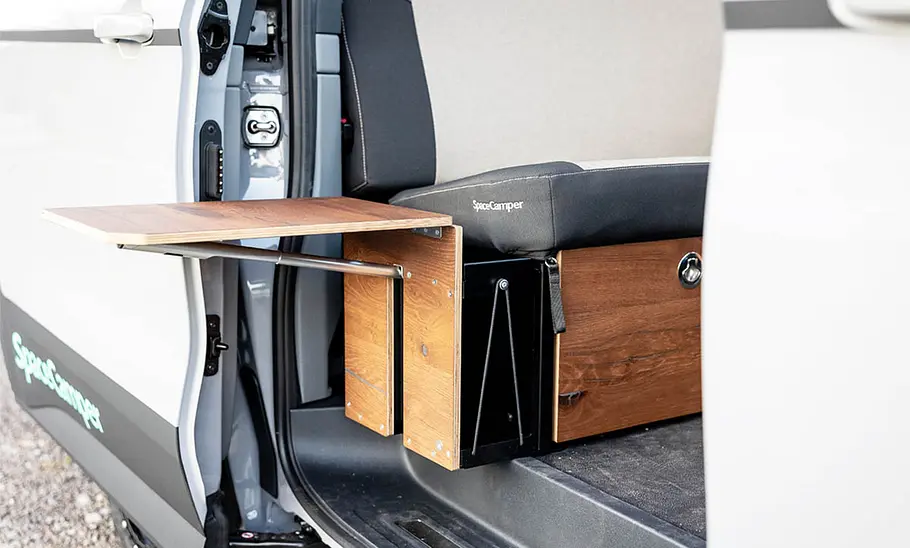 Spacecamper Classic+ Ford (2025) Die Detailaufnahme zeigt den beweglichen Tisch, der durch die Seitentüt des des Spacecamper Classic+ Ford (2025) ragt.