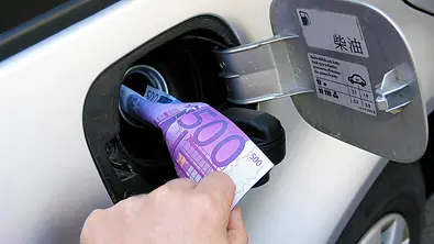 Spritkosten senken: Symbolbild zeigt Geldschein im Tankeinfüllstutzen eines Autos. - Foto: Imago