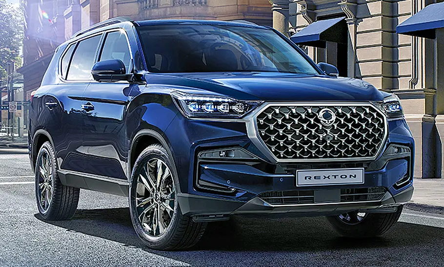 Das KGM Rexton Facelift (2021) steht in urbaner Umgebung, von vorne rechts fotografiert.