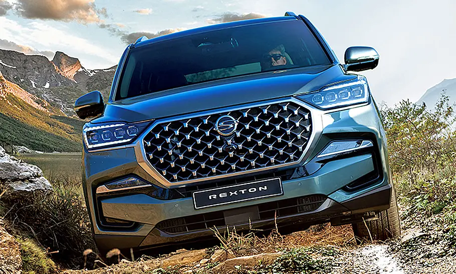 Das KGM Rexton Facelift (2021) fährt im Gelände eine Steigung hinauf, von vorne fotografiert.
