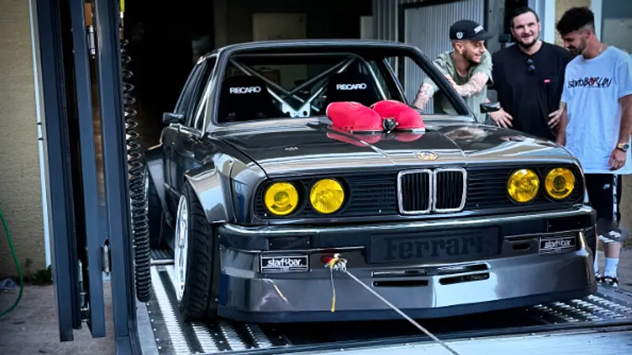 Starfobar BMW E30 mit Ferrari-V8 Drei Männer stehen neben dem Starfobar BMW E30 mit Ferrari-V8, fotografiert von vorne.