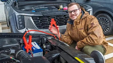 Redakteur Johannes Beck mit Überbrückungskabel beim Starthilfe geben am Auto. - Foto: AUTO ZEITUNG