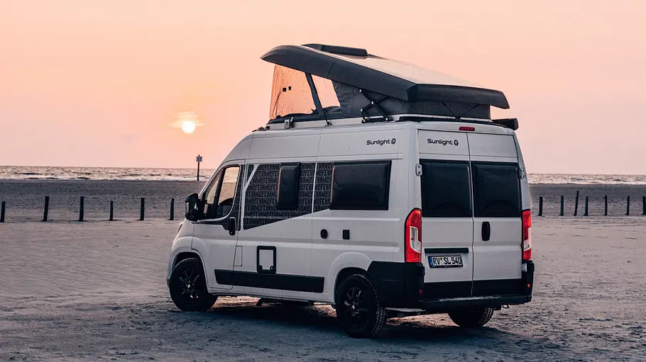 Sunlight Cliff 540V Vanlife Der Sunlight Cliff 540V Vanlife statisch von schräg hinten links mit geöffnetem Schlafdach bei Abendstimmung am Strand.