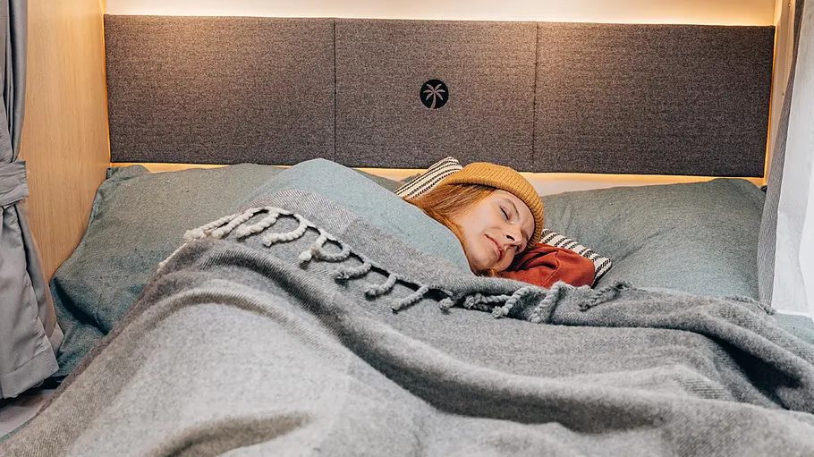 Die Innenaufnahme zeigt eine schlafende Frau im Heckschlafzimmer des Sunlight T58.