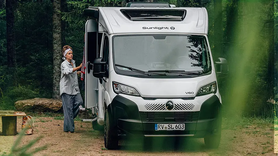 Der Sunlight V60 im Wald geparkt, Ansicht von vorn. Eine Person steht an der Eingangstür.