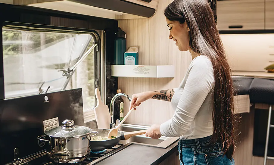 Sunliving C 70 DL (2025) Eine Frau steht in der Bordküche des Sunliving C 70 DL (2025) und kocht.