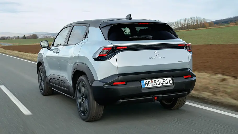 Der Suzuki e Vitara fährt auf einer Landstraße, von hinten links fotografiert.
