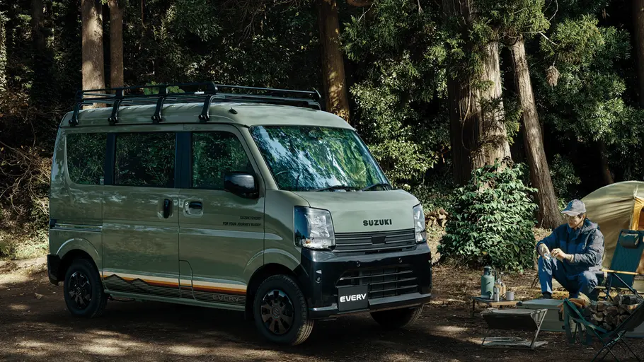 Der Suzuki Every statisch von schräg vorne rechts mit einem Wald im Hintergrund.