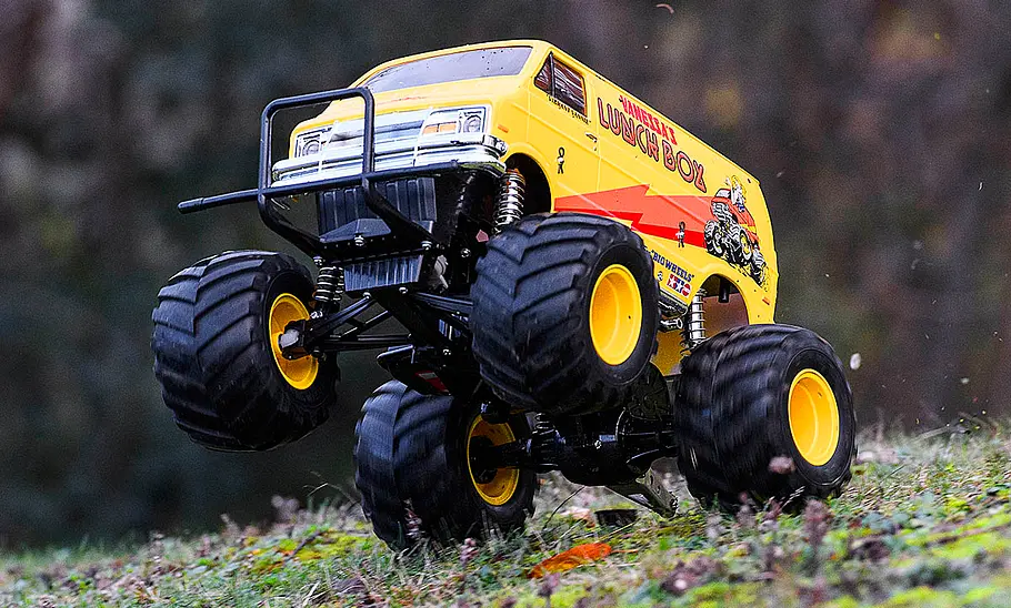 Das Bild zeigt den Tamiya Lunch Box fahrend von schräg vorne links fotografiert. Die Vorderräder sind in der Luft.