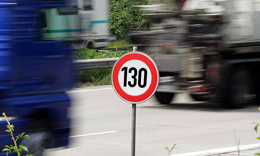 Ein Autobahnschild zur 130-km/h-Beschränkung im Vordergrund, vorbeifahrende Fahrzeuge im Hintergrund