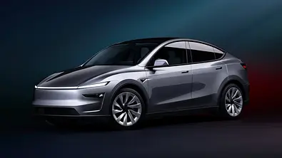 Das Tesla Model Y Facelift steht vor dunklem Hintergrund, von vorne links fotografiert. - Foto: Tesla