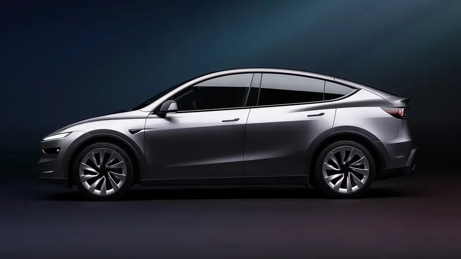Tesla Model Y Facelift Das Tesla Model Y Facelift steht vor dunklem Hintergrund, von links fotografiert.