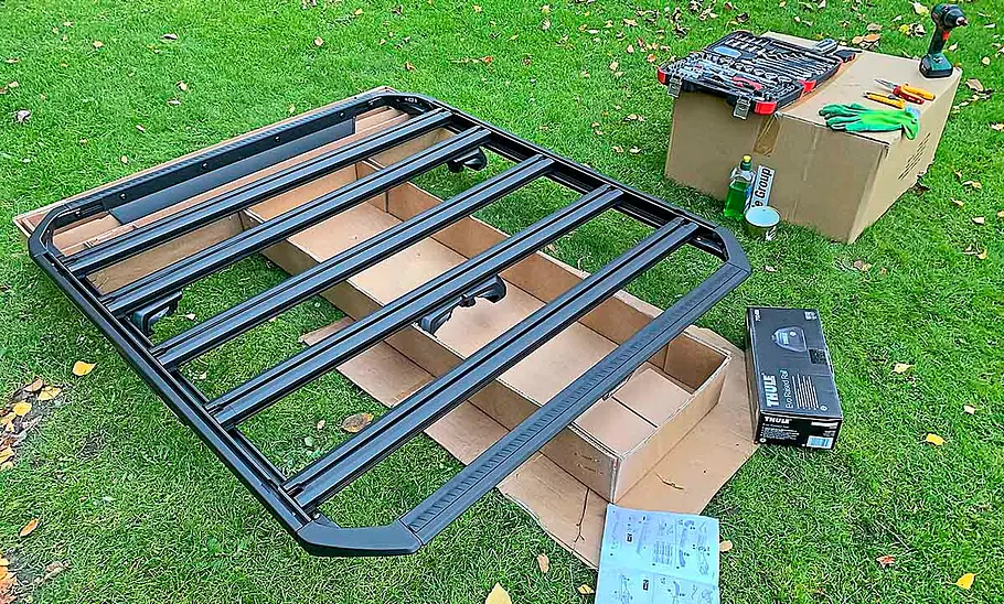 Dachplattform Thule Caprock ausgepackt und auf einer Wiese liegend.