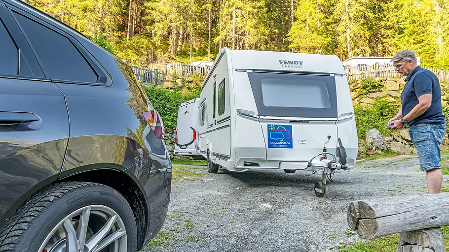 Tirol-Reisereportage im Fendt Bianco Der Fendt Bianco wird auf dem Campingplatz per Mover eingeparkt. Eine Person steht rechts im Bild mit einer Fernbedienung.