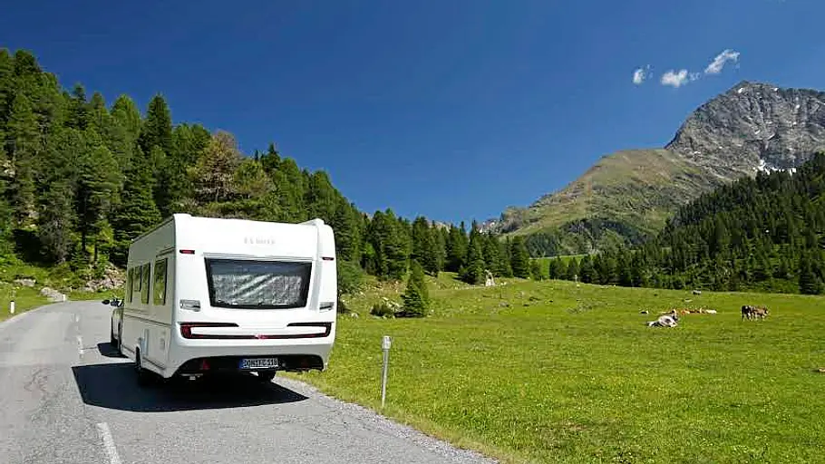 Tirol-Reisereportage im Fendt Bianco Das Gespann aus BMW X3 und Fendt Bianco auf einer Landstraße in Tirol. Neben der Straße weiden Kühe.