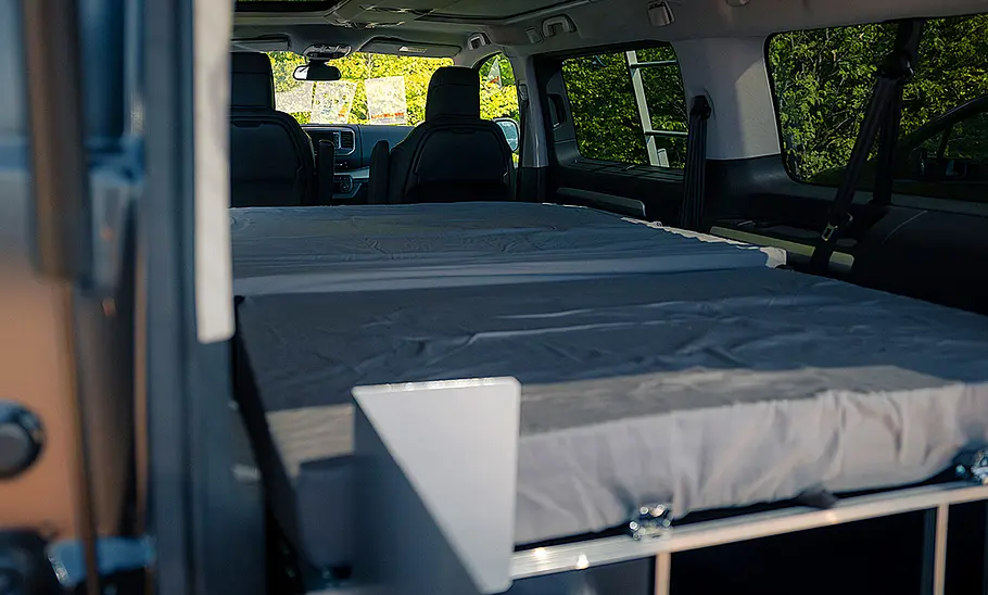 Toyota-Campingzubehör; Toyota Proace Verso, stehend, Blick durch die Heckklappe. Im Van befindet sich eine Campingbox.
