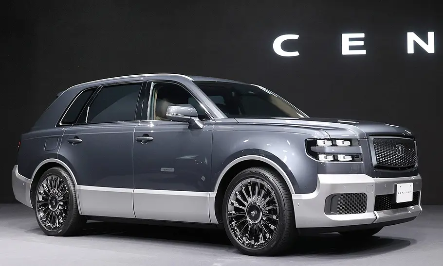 Toyota Century (2023) Das SUV Toyota Century stehend auf einer Messebühne, dahinter sieht man den Anfang des Schriftzuges Century.