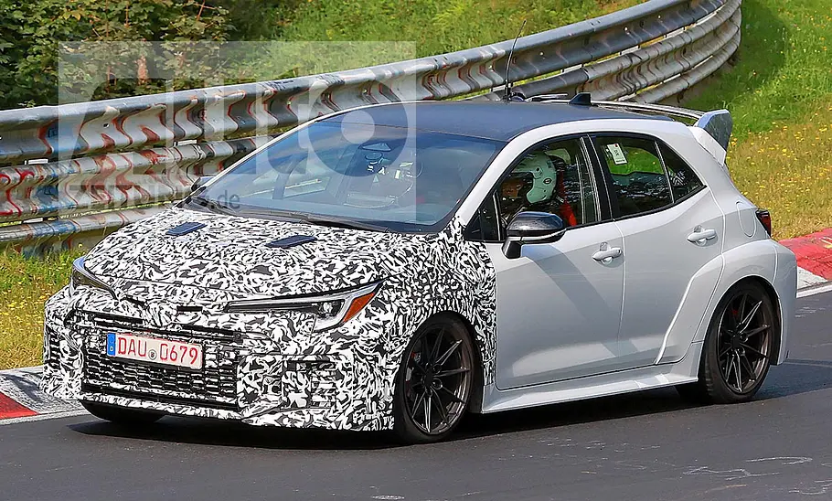 Toyota Corolla GRMN (2025) Toyota GR Corolla Facelift (2024); Blick von schräg links vorne auf den fahrenden, teilweise getarnten Corolla.