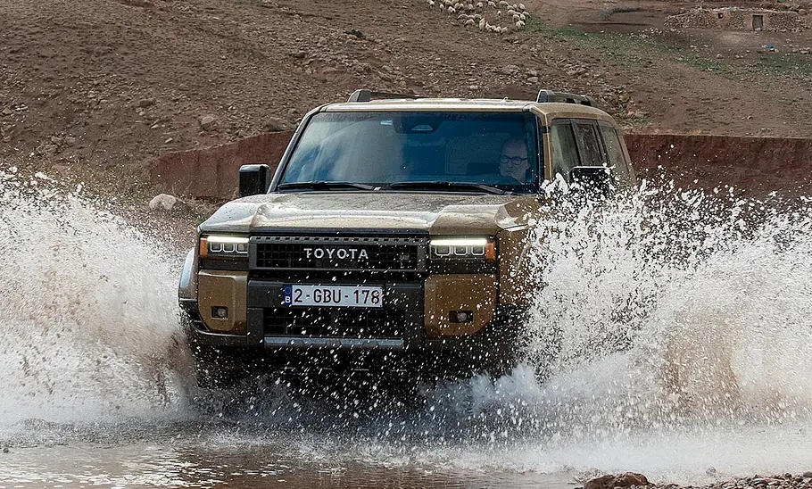 Toyota Land Cruiser (2024) Der Toyota Land Cruiser (2024) fährt durch Wasser; von vorne fotografiert.