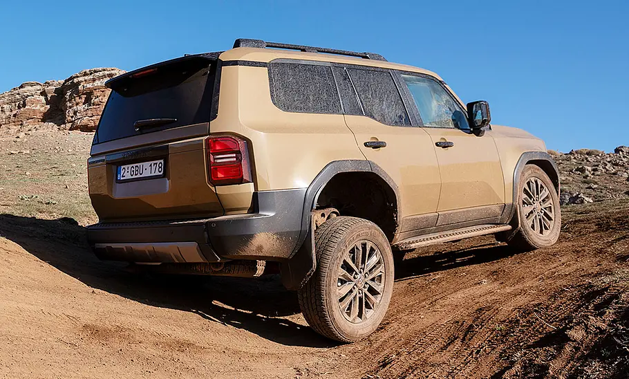 Toyota Land Cruiser (2024) Der Toyota Land Cruiser (2024) statisch im Gelände, die Achsen stark verschränkt; von schräg hinten fotografiert.