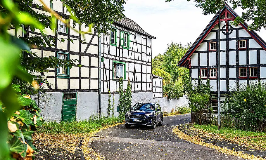 Der Toyota RAV4 fährt auf einer Dorfstraße zwischen mehreren Fachwerk-Häusern entlang.