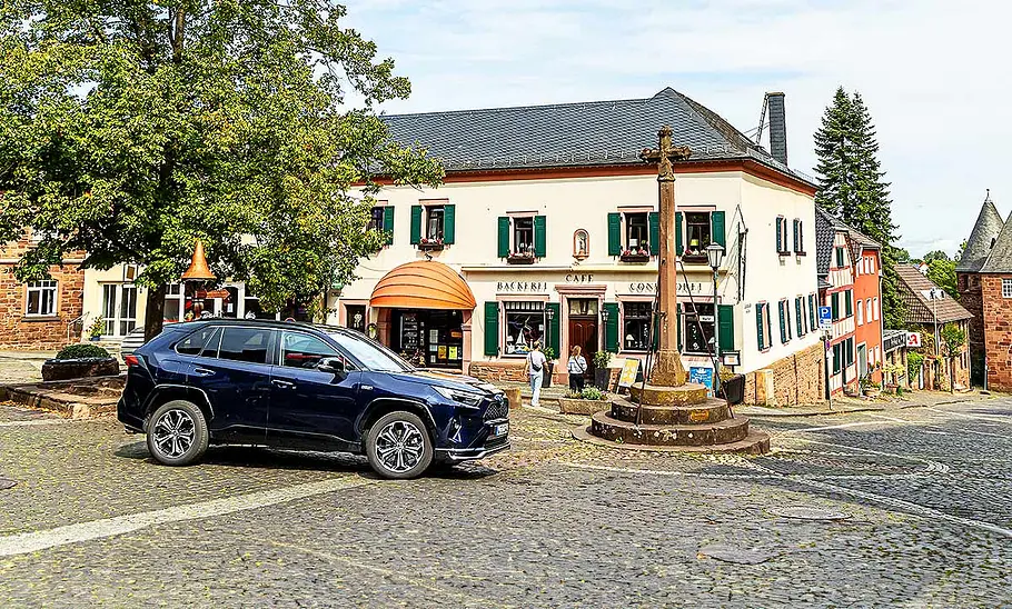 Blick von der Seite auf den Toyota RAV4, der auf einem gepflasterten Dorfplatz steht.