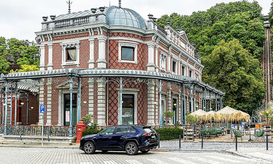 Blick von der Seite auf den Toyota RAV4, der vor einem alten Gebäude steht.