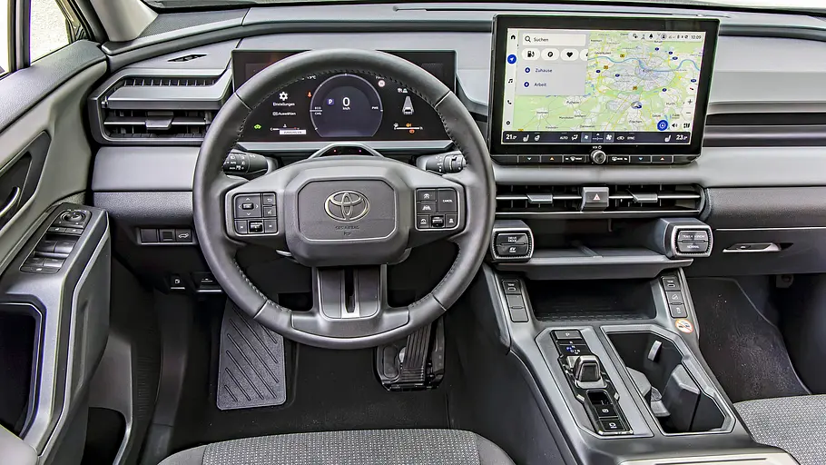 Toyota RAV4 und VW Tiguan im Vergleich Das Toyota-Cockpit zeigt ein Lenkrad, digitale Instrumente, einen großen Navigationsbildschirm und eine Mittelkonsole.