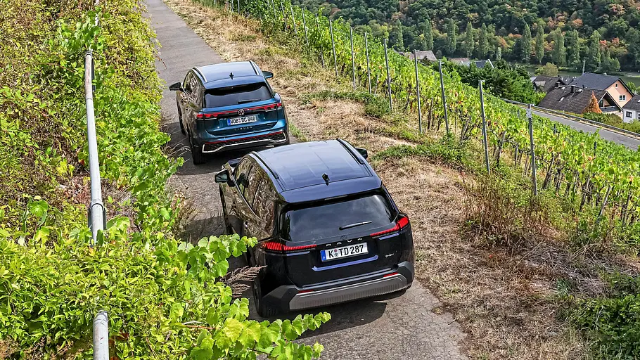 Toyota RAV4 und VW Tiguan im Vergleich Ein Toyota RAV4 und ein VW Tiguan stehen auf einer schmalen Hangstraße über einem Flusstal mit Weinbergen und einer Ortschaft.