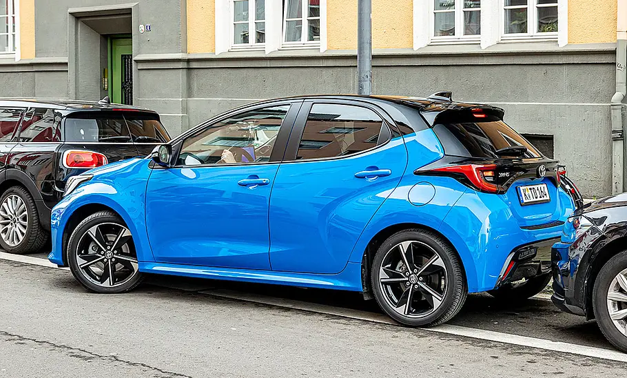 Toyota Yaris 1.5 VVT-i Hybrid 130 Der Toyota Yaris 1.5 VVT-i Hybrid 130 parkt in einer Parklücke seitlich ein, von schräg hinten fotografiert.