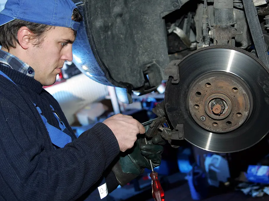 Eine Person arbeitet an den Bremsbelegen eines Autos.