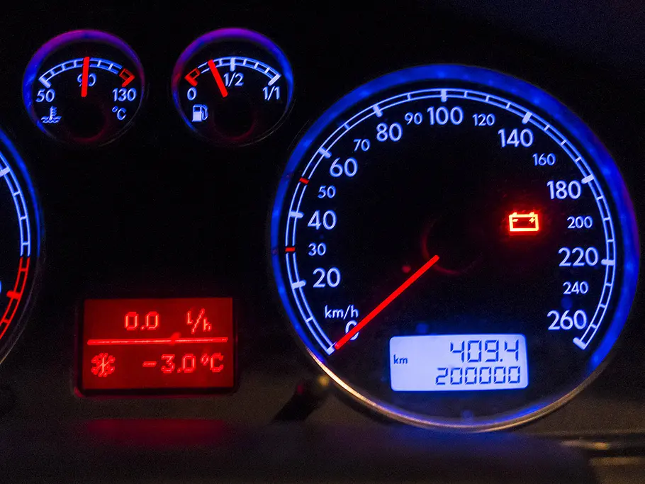 Ein Mulitinstrument im Auto in der Nahaufnahme. Das Batteriesymbol leuchtet.