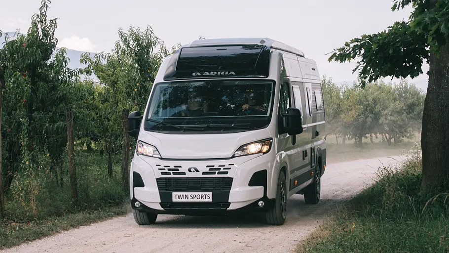 Der Adria Twin Sports auf einer Schotterstraße fahrend von schräg vorne links.
