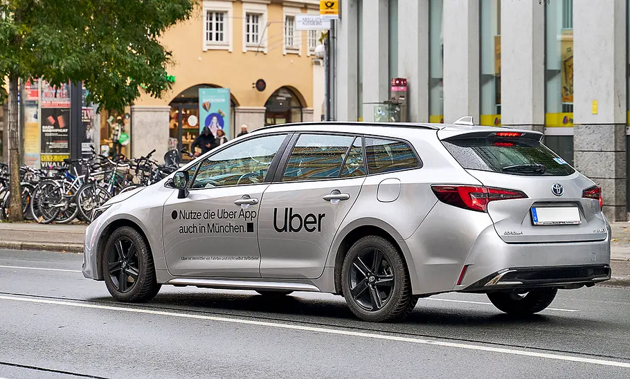 Ein fahrender Toyota Corolla als Uber-Fahrzeug auf einer Straße von schräg hinten.