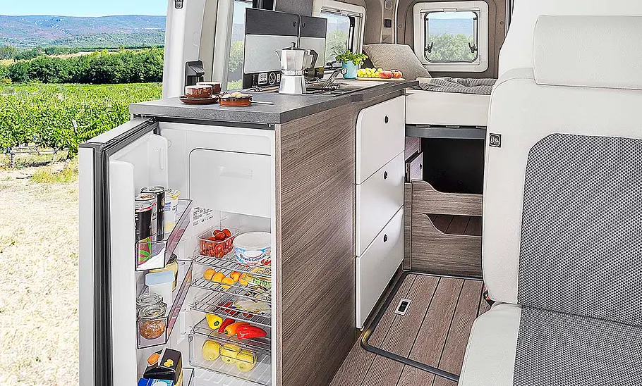 Das Bild zeigt die Küche des Van Tourer Ford 600 D (2024) mit geöffnetem Kühlschrank.