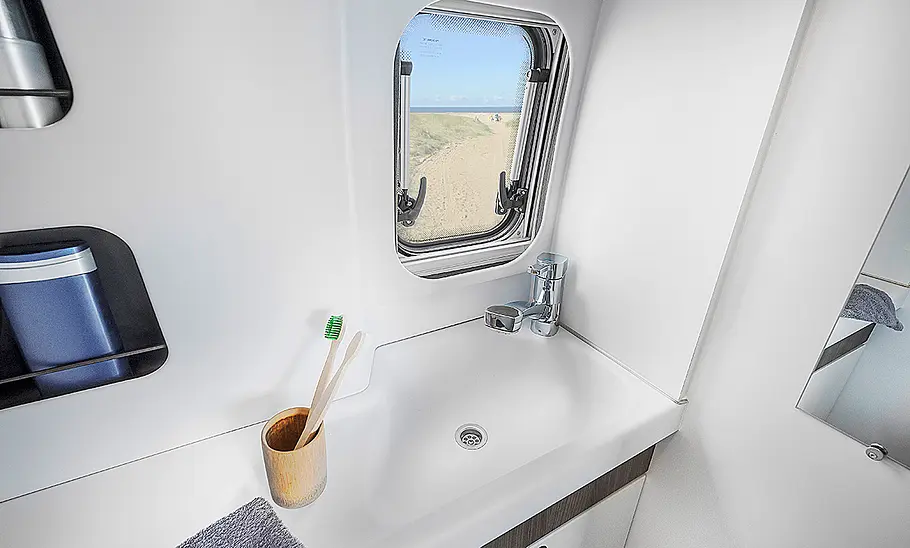 Das Bild zeigt das Seitenfenster und das Waschbecken im Bad des Van Tourer Ford 600 D (2024).