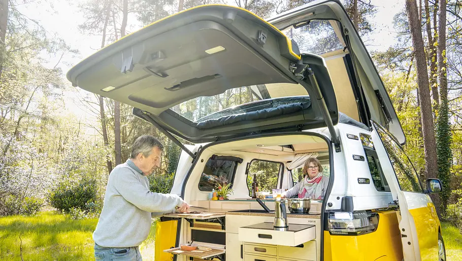 Ventje T7 Camper Das von außen aufgenommene Foto zeigt das Küchenmodul im Heck eines Ventje-Campers und zwei Personen.