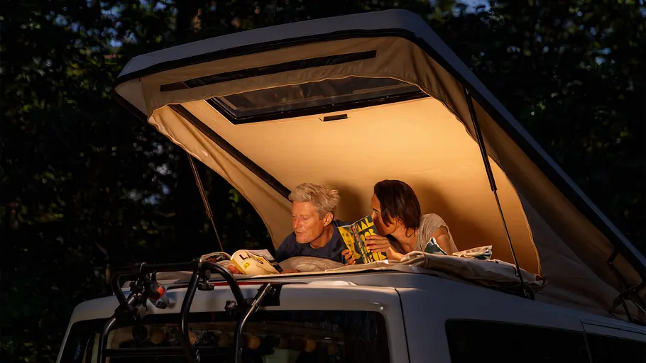 Zwei Personen im Aufstelldach des Ventje T7 Camper von außen durch das offene Zeltbalg fotografiert.