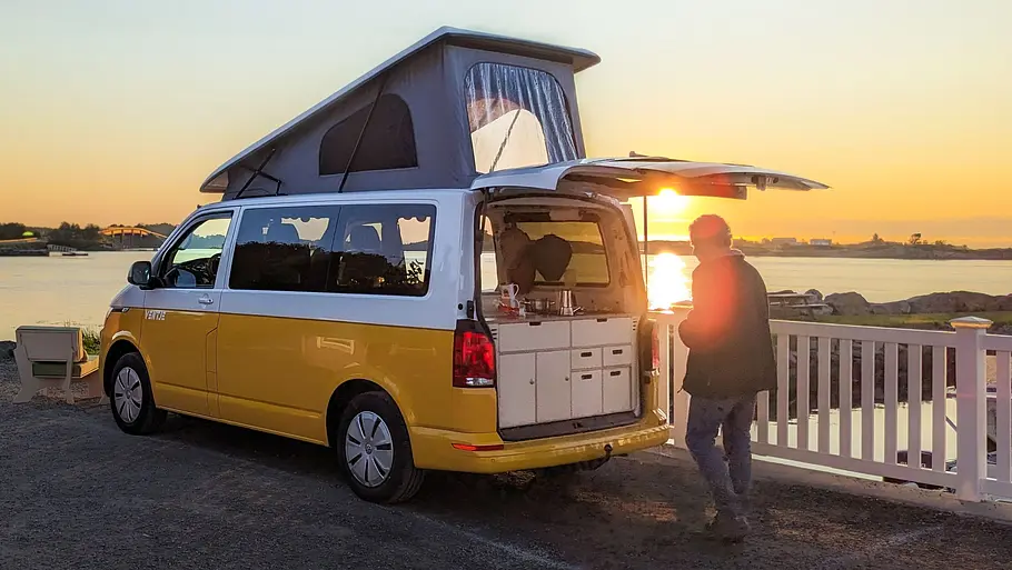 Ventje T7 Camper Die Außenaufnahme zeigt einen Ventje-Camper (T6) mit aufgestelltem Aufstelldach von schräg hinten.