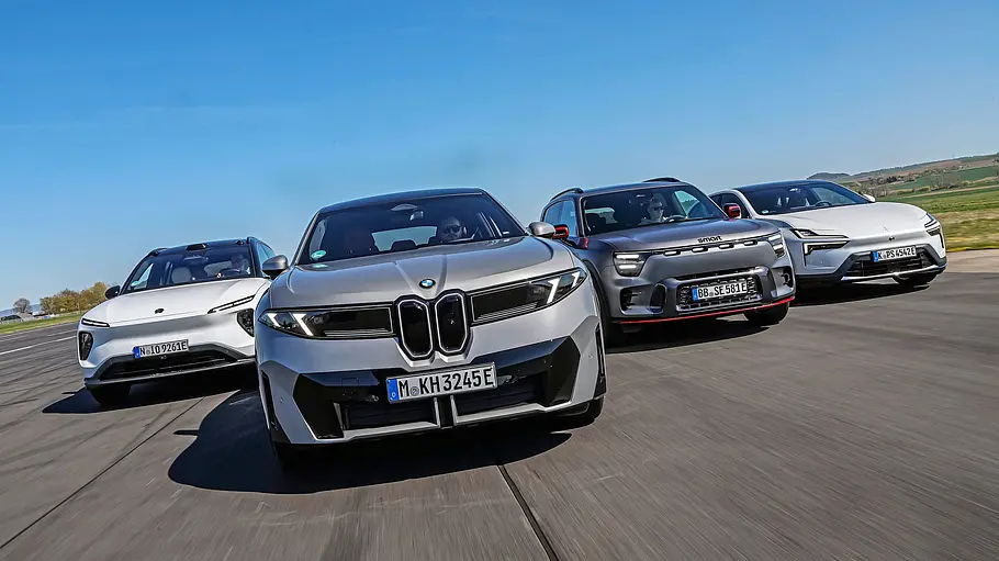 Vergleichstest BMW iX3, Polestar 4, Nio EL6 und Smart #5 BMW iX3, Polestar 4, Nio EL6 und Smart #5 fahren nebeneinander auf einer breiten Asphaltstrecke. Ein silberner BMW steht im Vordergrund unter blauem Himmel.