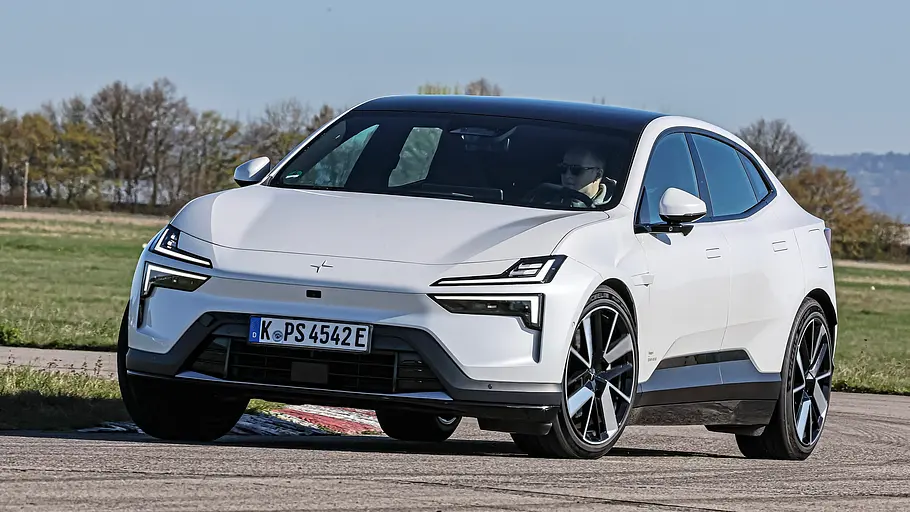 Vergleichstest BMW iX3, Polestar 4, Nio EL6 und Smart #5 Ein weißer Polestar 4 fährt auf einer asphaltierten Strecke. Im Hintergrund liegen Wiesen und Bäume.