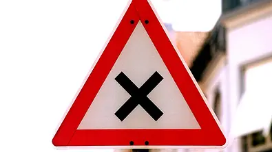 Das Verkehrszeichen 102 signalisiert dem Autofahrenden, dass er sich auf eine Kreuzung oder Einmündung mit einer Vorfahrt von rechts zubewegt.
