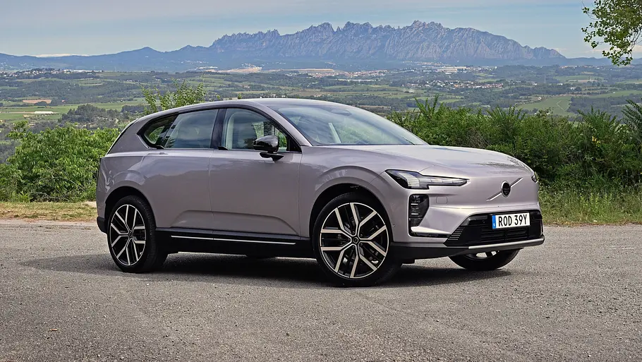 Volvo EX60 Der Volvo EX60 steht vor einem Gebirgspanorama, von vorne rechts fotografiert.