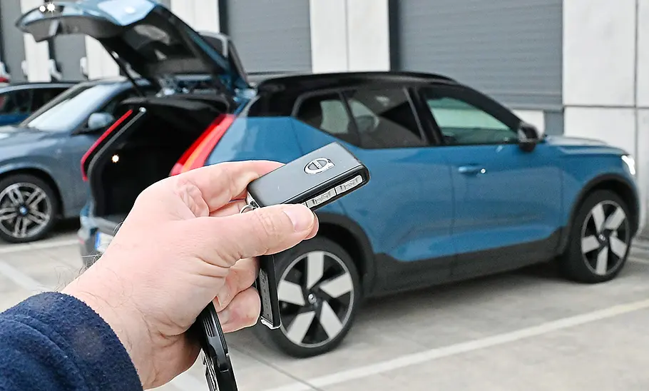 Bild zeigt eine Hand, die den Schlüssel des Volvo XC40 Recharge Extended Range bedient, im Vordergrund, im Hintergrund ist der Volvo XC40 Recharge Extended Range zu sehen.