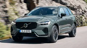 Der Volvo XC60 (2025) fährt auf einer Landstraße, von schräg vorne fotografiert. - Foto: Volvo