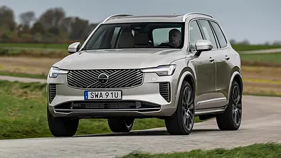 Das Volvo XC90 Facelift (2024) fährt über eine Landstraße, von schräg vorne fotografiert. - Foto: Volvo