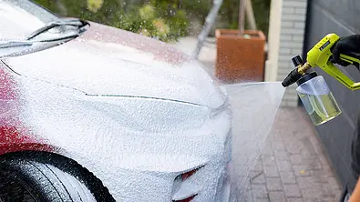 Ein roter Toyota wird mit Snow Foam besprüht. - Foto: Imago