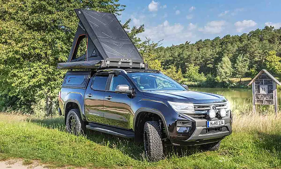 VW Amarok mit Hardtop, Markise und Dachzelt; stehend, schräg vorne mit aufgeklapptem Dachzelt